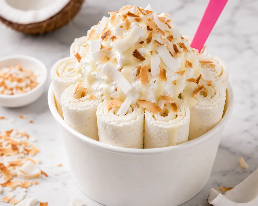 Creamy Coconut rolled ice cream with coconut flakes and condensed milk drizzle